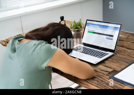 La donna si è addormentato in attesa del bianco per rallentare il download sul computer portatile Foto Stock
