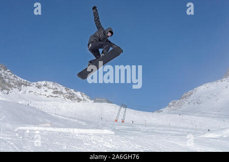 Uno snowboarder è il salto a un funpark vicino alla stazione a monte Schaufeljoch sulla parte superiore del Ghiacciaio dello Stubai in Tirolo, Austria. Foto Stock