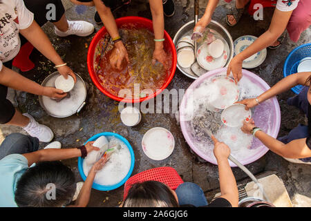 Le donne lavare le loro stoviglie, bacchette e posate all'interno delle antiche mura della città di Zhaoqing in Cina. Lavaggio comunale up è un passatempo molto diffuso Foto Stock