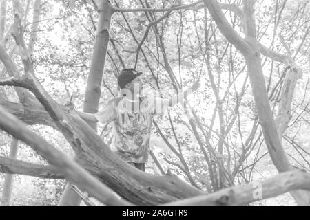Un cheeky poco ragazzo seduto in un cornfield indossando un cappello da baseball, mentre fuori a giocare con gli amici Foto Stock