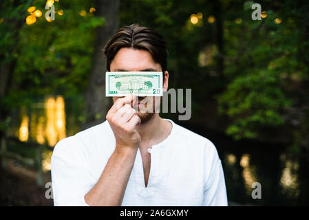 Chi detiene un dollaro, nasconde la sua faccia di censurare la sua personalità dal capitalismo. Foto Stock