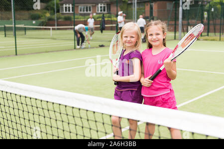 Due giovani ragazze che praticano la loro abilità di tennis presso il locale tennis club, corte Foto Stock