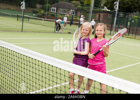 Due giovani ragazze che praticano la loro abilità di tennis presso il locale tennis club, corte Foto Stock