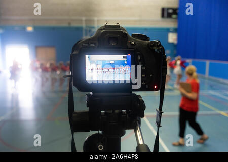 Un videografo registra un concorso di danza giudicati in un arena sportiva Foto Stock