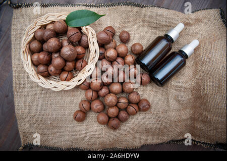 Olio di Macadamia in bottiglie e noci di macadamia, piana, laici vintage stile rustico . Bio, organico , natura concetto cosmetici Foto Stock