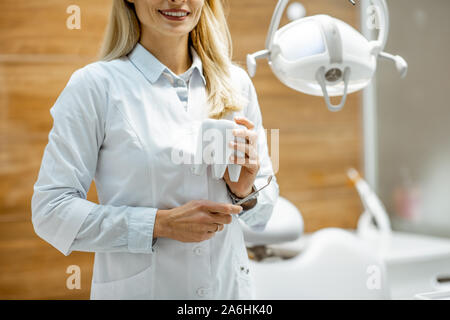 Ritratto di un fiducioso dentista con modello di denti presso lo studio dentistico. Immagine ritagliata, focalizzata sulle mani Foto Stock