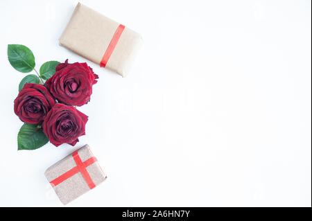 Piatto sfondo laici, flower pattern, il giorno di San Valentino, il tema di amanti. Rose rosse e doni con i nastri su uno sfondo bianco, isolato Foto Stock