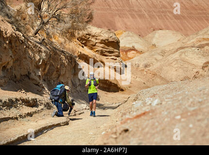 Regista di documentari di scatto su runner atleta sul sentiero selvaggio a montagne di argilla nel deserto Foto Stock