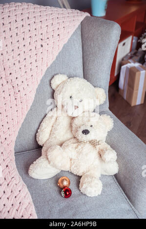 Due bianchi toy orsetti su una sedia e una morbida rosa plaid, Capodanno umore Foto Stock