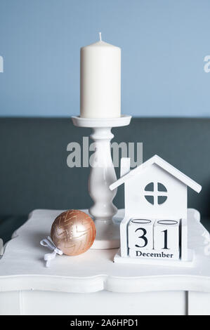 Grande cero bianco, palla di Natale e calendario in legno con la data 31 dicembre foto in delicati colori pastello. Umore di natale Foto Stock