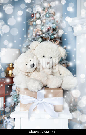 Natale umore, due giocattolo bianco orsetti contro lo sfondo di un bianco albero di Natale decorato. In attesa di un miracolo, Nuovo Anno decorazioni Foto Stock