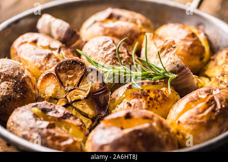 Patate arrosto con aglio spezie ed erbe in padella vintage Foto Stock