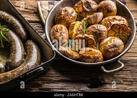 Patate arrosto con jitrnice jaternice aglio spezie ed erbe in padella vintage Foto Stock