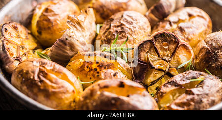 Patate arrosto con aglio spezie ed erbe in padella vintage Foto Stock