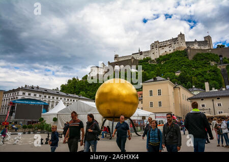 Piazza Kapitelplatz con Stephan Balkenhol - Sphaera, una scultura di un uomo su una sfera dorata su Kapitelplatz a Salisburgo città vecchia, Austria. Foto Stock