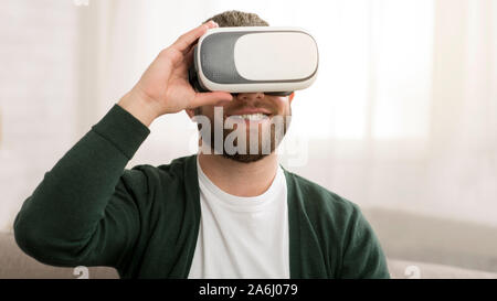 Gioioso uomo di mezza età cercando occhiali vr a casa Foto Stock