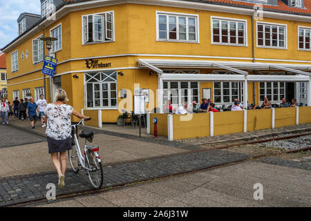 Donna con una bicicletta a piedi nella parte anteriore del ristorante è visto in Skagen, Danimarca il 28 luglio 2019 Skagen Danimarca è la città più settentrionale, sulla costa orientale di Skagen Odde penisola nel lontano nord dello Jutland. © Michal Fludra / Alamy Live News Foto Stock