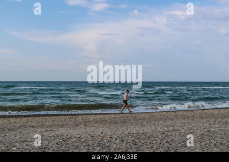 Donna con poli escursioni a piedi lungo la costa del Mare del Nord in cerca di rifiuti gettati fuori dal mare sulla spiaggia tra cui reti da pesca, dei rifiuti di plastica, bottiglie è visto sulla spiaggia del Mare del Nord a Skagen, Danimarca il 28 luglio 2019 © Michal Fludra / Alamy Live News Foto Stock