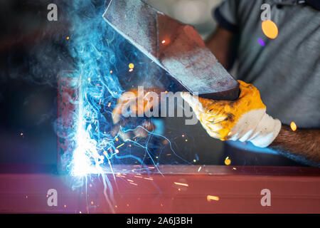Lavoratore di metallo è la saldatura metalli con protezione di lui self. Foto Stock