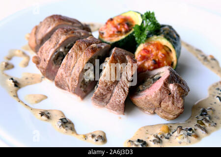 Rotolo di carne con ripieno di funghi. Fette di rotolo su una piastra con salsa. Foto Stock