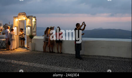 Fira, Grecia - 14 Luglio 2019: turisti scattare foto delle opinioni su una notte estiva in Fira su Ipapantis Foto Stock