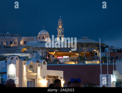 Fira, Grecia - 14 Luglio 2019: la torre dell orologio e la cupola di San Giovanni Battista cattedrale di notte visto da Ipapantis Foto Stock