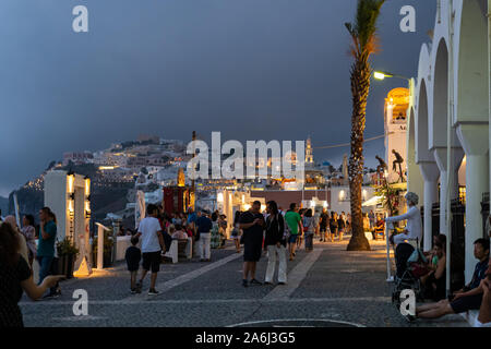 Fira, Grecia - 14 Luglio 2019: notte tempo colpo di turisti a piedi lungo la scogliera di strada Ipapantis Foto Stock