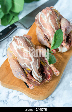 Due nuove materie fagiani avvolto in pancetta preparato per la cottura sul pannello di legno Foto Stock