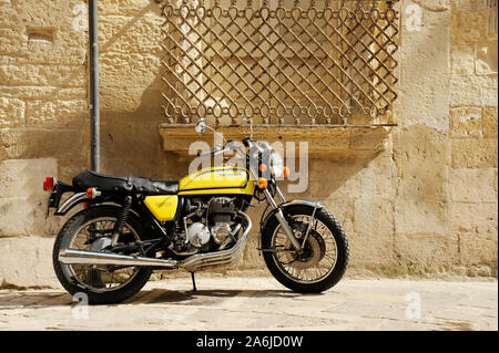Giallo Honda 400 motociclo in piedi in strada della vecchia città italiana. Lecce, Puglia, Italia Foto Stock