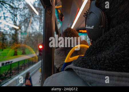 Retro della testa di uomo che indossano le cuffie al piano superiore di un bus Foto Stock