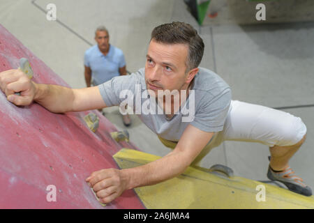 Uomo di mezza età su indoor parete di arrampicata Foto Stock