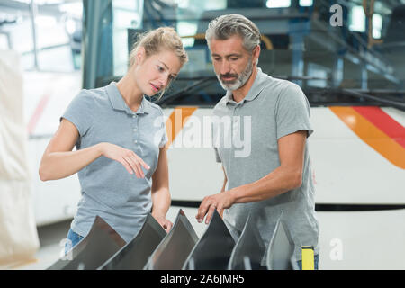 Lavoratori di sesso femminile e maschile in bus garage Foto Stock