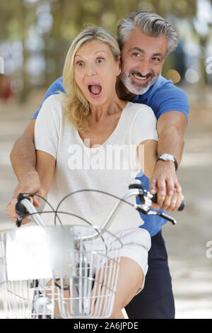 Felice Coppia matura divertirsi su una bicicletta Foto Stock