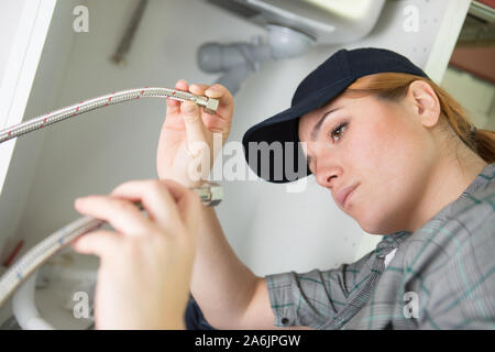 Plumber donna di installare il lavandino in bagno Foto Stock