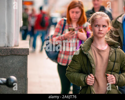 Mosca, Russia - 19 Ottobre 2019: una ragazza cammina per la strada tra una folla di persone. Passanti in background di autunno caldo weekend di sole Foto Stock
