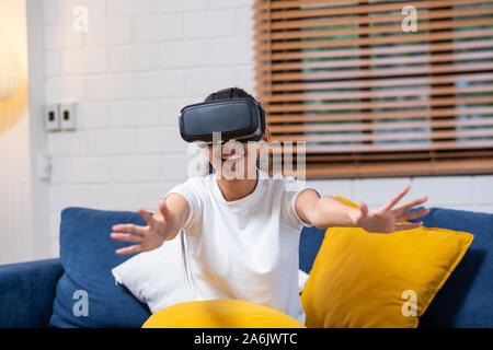 Giovane donna asiatica toccando aria durante il VR esperienza di realtà virtuale che indossa gli occhiali di realtà .futuro concetto di tecnologia Foto Stock