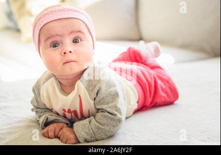 6 mesi Baby girl giacciono su un lettino in luminoso soggiorno. Foto Stock