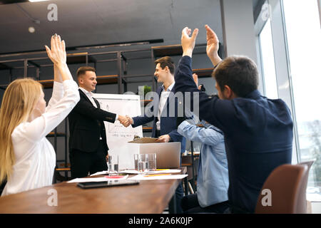 Allegro slim bello handshaking boss, complimentandomi con il collega la promozione, valorizzando il buon risultato di lavoro. la felicità e il successo, celebrazione Foto Stock