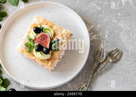 Pavlova su un biscotto con una delicata crema di cagliata, fichi e uva. Una nuova variante del classico dolce Australiano. Foto Stock