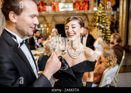 Bella ben vestito matura per celebrare il nuovo anno di vacanza, in piedi insieme con sparcle vino presso il ristorante di lusso con altre persone sullo sfondo Foto Stock