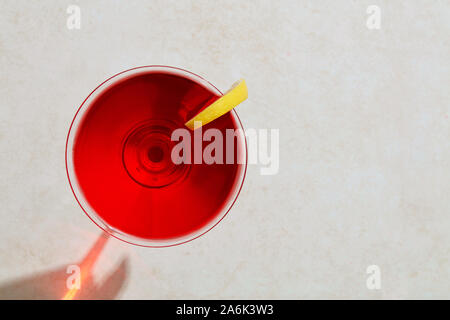Red cocktail Martini in vetro con limone duro sotto la luce del sole estivo. Vista aerea con copia spazio. Foto Stock