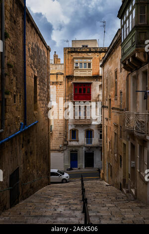 Vecchia città di La Valletta a Malta, scale e tradizionale maltese case in pietra con balconi. Foto Stock