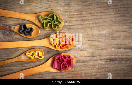 Colorato forma di cuore maccheroni su cucchiai di legno Foto Stock