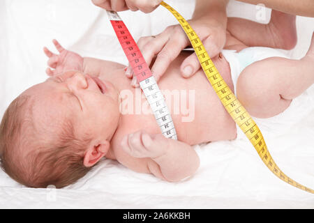 Pediatra esamina due settimana di età bambino. Medico usando il nastro di misurazione controllo del neonato Dimensioni torace. Neonato check-up del concetto Foto Stock