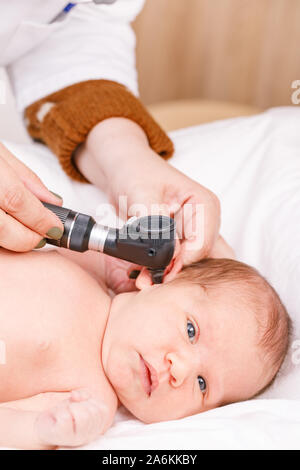 Pediatra esamina due settimane di età del bambino orecchio in clinica pediatrica. Medico utilizzando otoscopio (auriscope) per verificare il canale uditivo e la membrana del timpano. Neonato Foto Stock