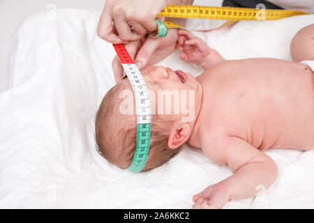 Pediatra esamina due settimana di età bambino. Medico usando il nastro di misurazione controllo del neonato dimensioni di testa. Neonato check-up del concetto Foto Stock