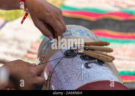 Antica tecnica di tessitura con bastoni di legno e ganci su un modello Foto Stock