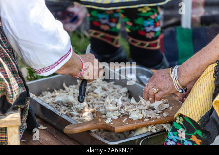 Vecchia donna disossare la carne di pollo per la tradizionale zuppa bulgara chiamato Kurban. Foto Stock