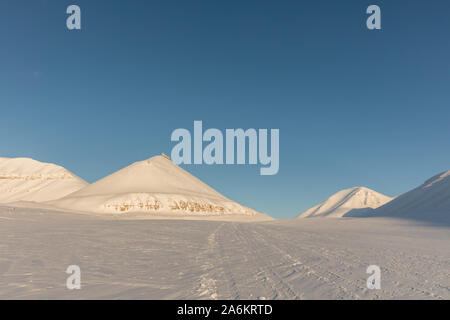 Tracce di motoslitte in artico paesaggio invernale con montagne coperte di neve sulle Svalbard, Norvegia Foto Stock