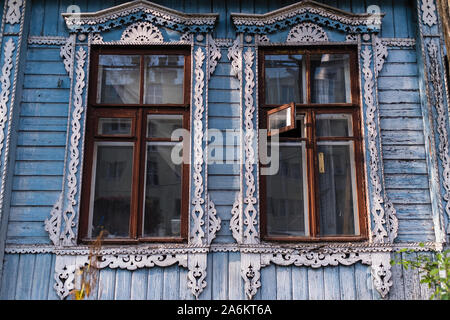 Finestre sulla facciata di una casa in legno con architravi scolpiti. Foto Stock